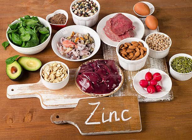 An image of foods with Zinc to explain benefits. A variety of zinc-rich foods, including seafood, leafy greens, nuts, seeds, and meat, displayed for promoting a balanced, nutrient-dense diet. Click to Learn More. 