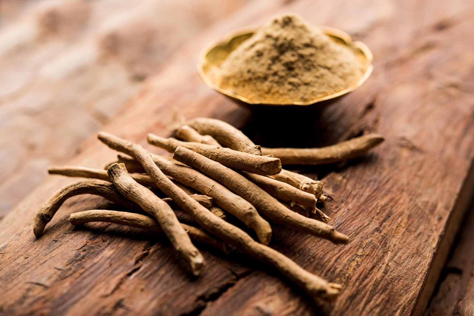 Image of Ashwaganha to explain benefits.  Raw ashwagandha roots and powder in a wooden bowl on wooden table. Click to Learn More. 