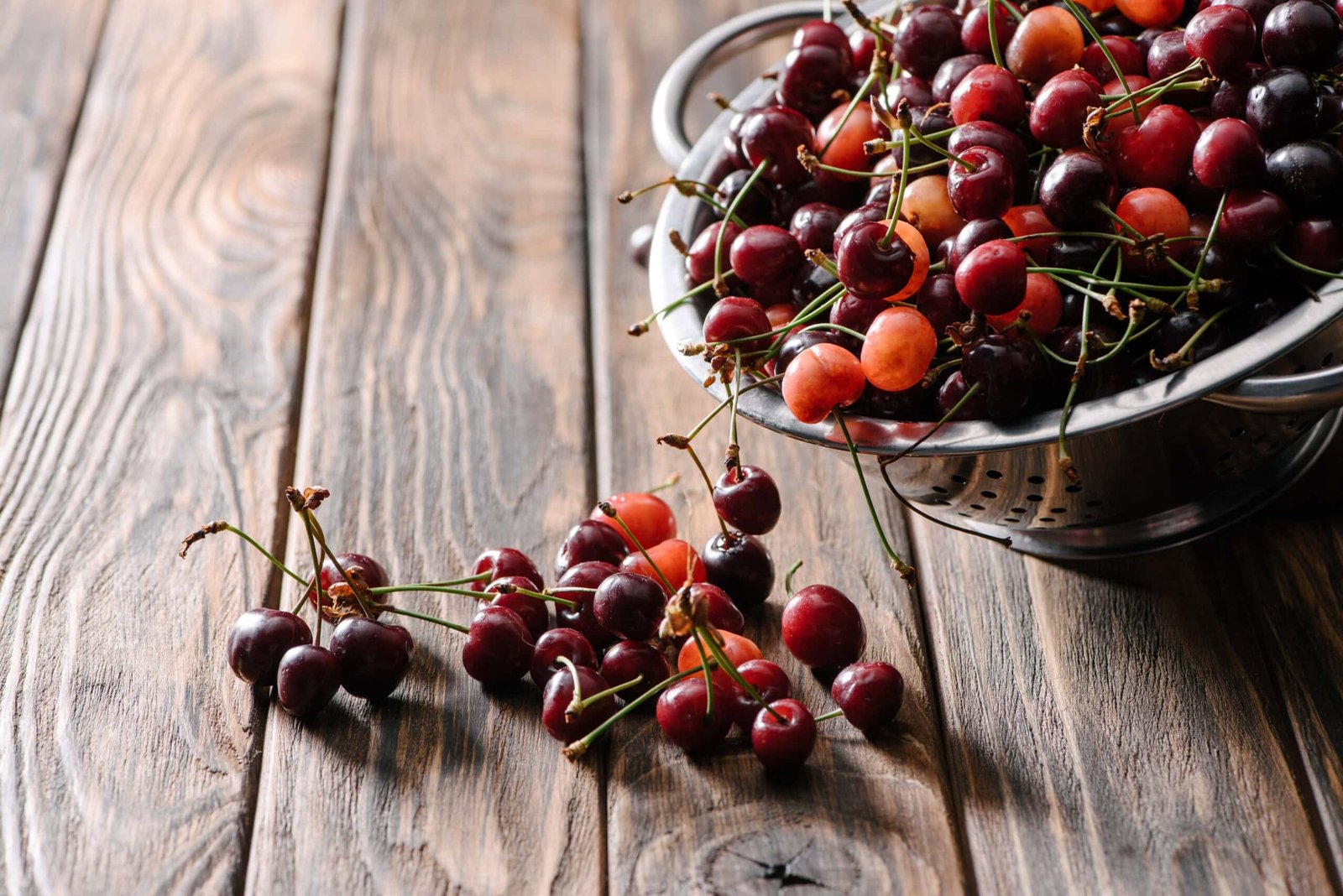 Image is to help describe Melatonin as an ingredient. Showing alive fresh tart cherries on a wooden bowl on an aged wooden table.  Click to Learn More.