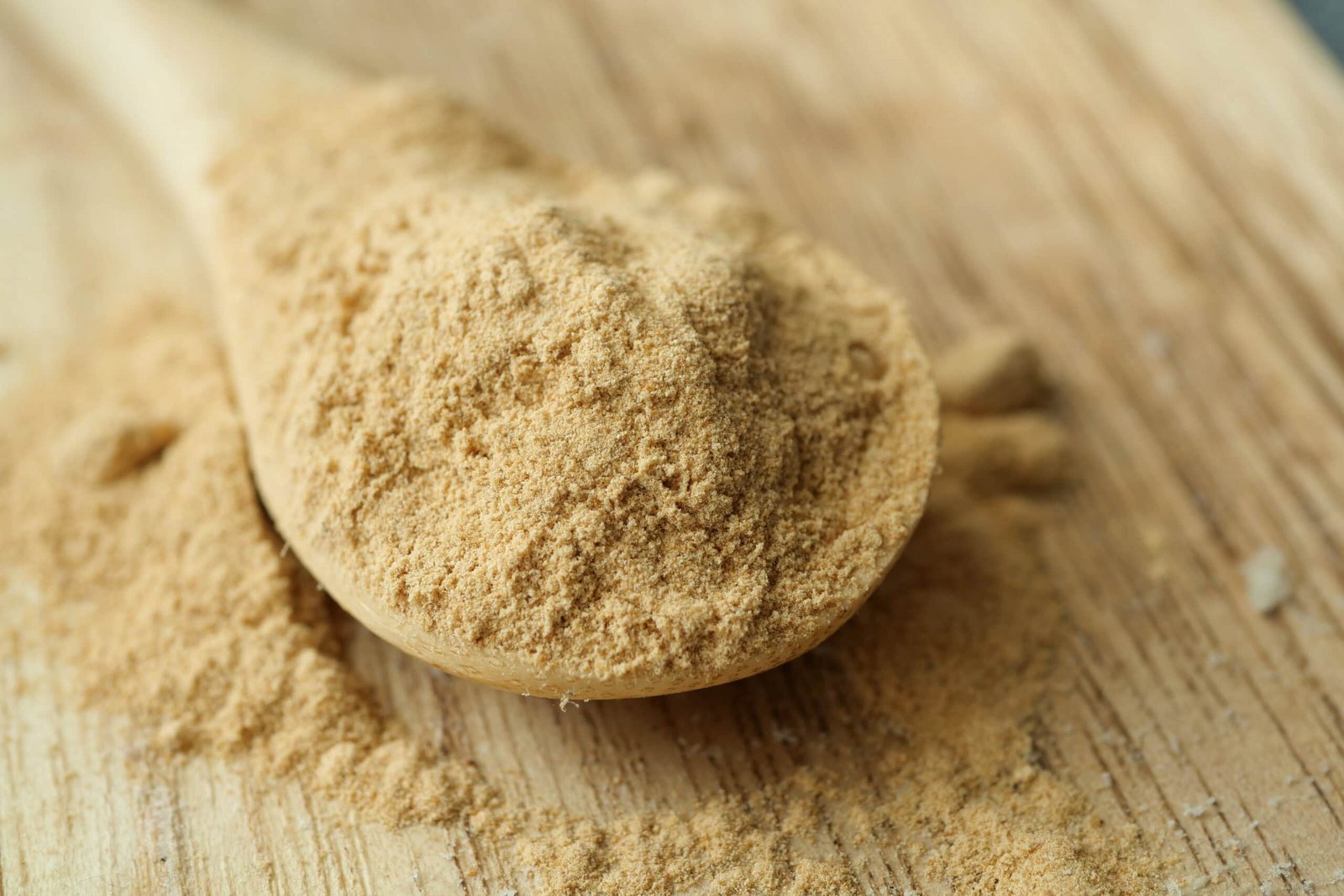 Image to show benefits of Maca Root.  Maca Root powder overflowing in a wooden spoon on a wooden table. Click to Learn More. 