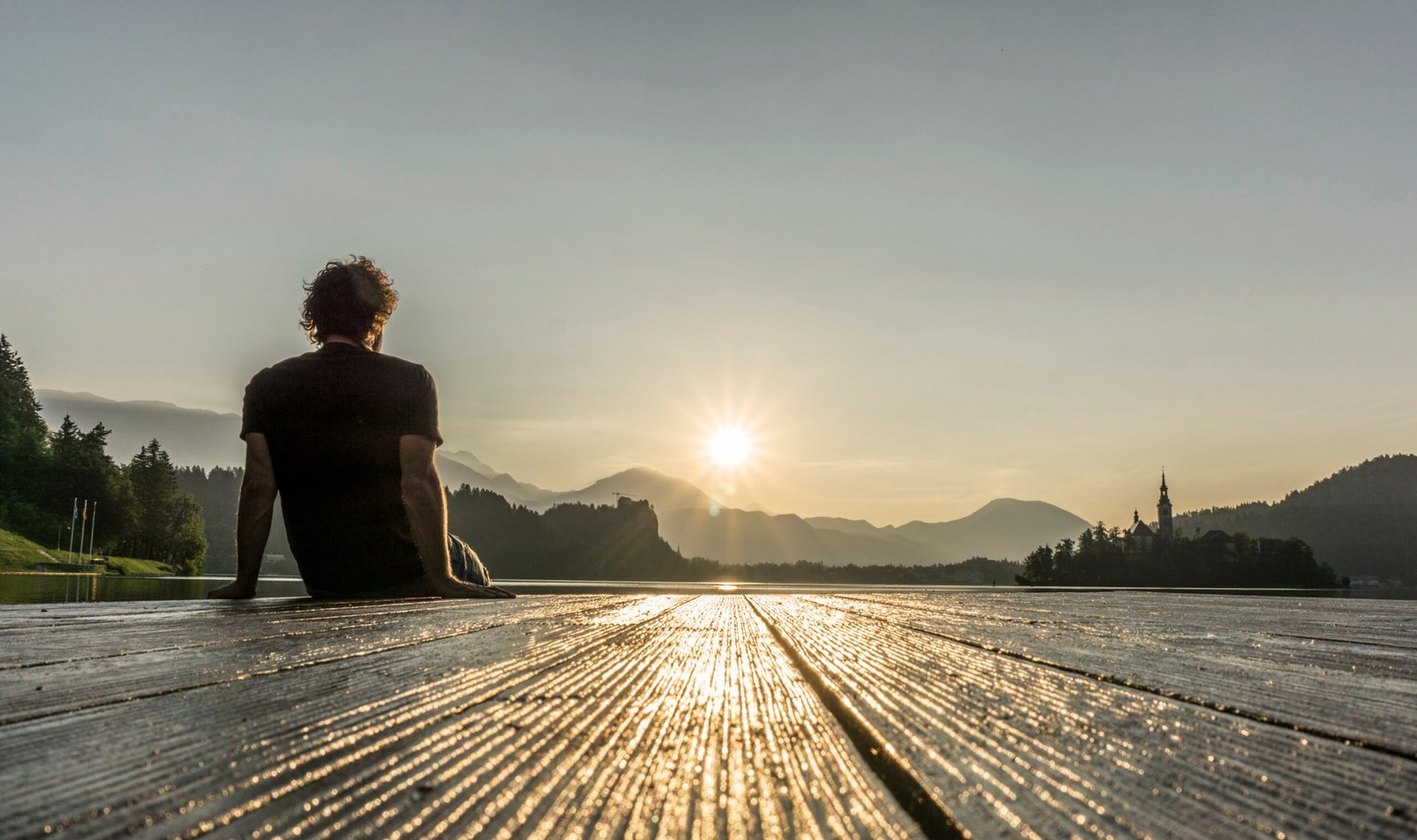 man on the pier observing the sunrise at lake bled 2023 11 27 04 53 49 utc scaled