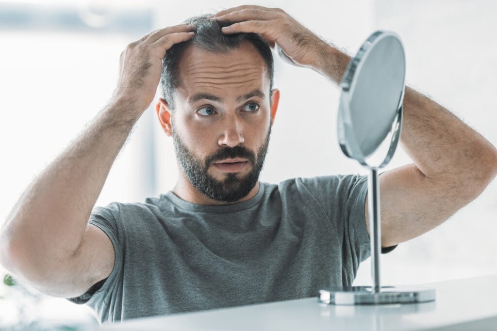 Saw Palmetto: Your Secret Weapon for Hair Growth 1 Man noticing his thinning hair in the mirror - could a natural solution like Saw Palmetto help?