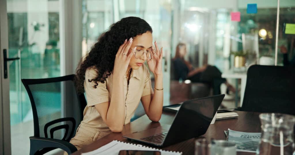 Benefits of Adaptogens for Stress Reduction Management 1 A woman at work with elbows on the desk and rubbing her temples and looking tired. What can help with stress reduction management.