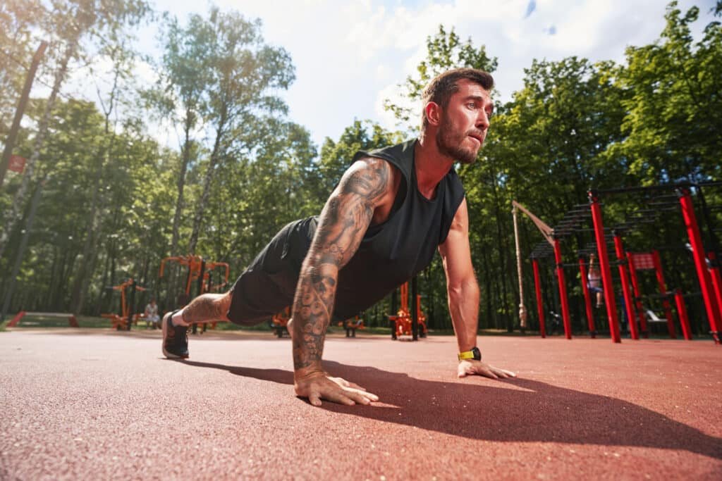 Adaptogens for Athletes: Top 5 Recovery Herbs Backed by Research 17 Supporting adaptogens for athletes, male athlete doing pushups in an outdoor park training area.