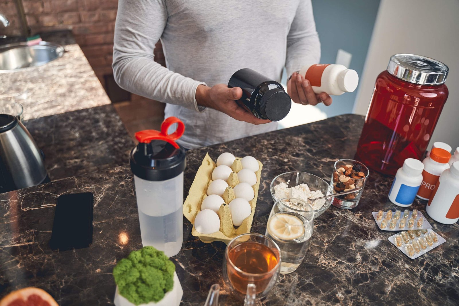 Man organizing his meals and supplement stacking guide on kitchen island to improve his busy schedule