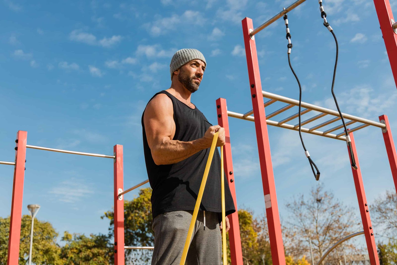 Sportsman exercising with resistance band on sports ground due to taking botanical extracts to maximize gains.