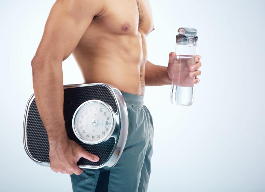 Diet for High Cortisol: How Dads Can Combat Weight Gain 7 a man holding a scale and a water bottle. Diet for High Cortisol article