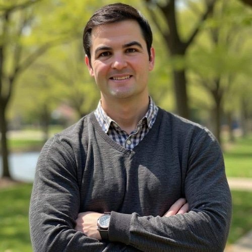 A man taking a selfie with his do in an open field. It's fall and cool outside.